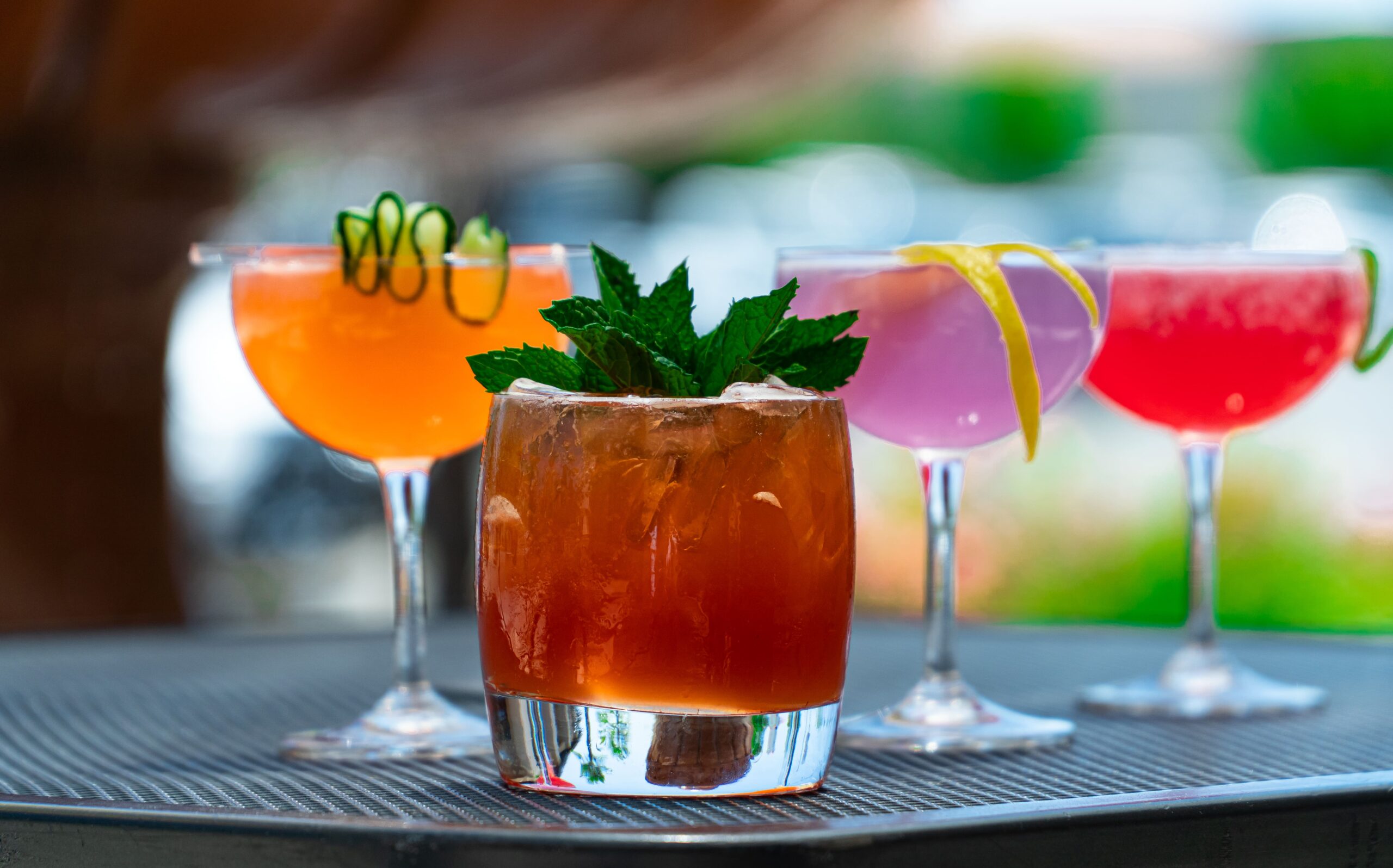 a row of cocktails with garnishes on a sunny day