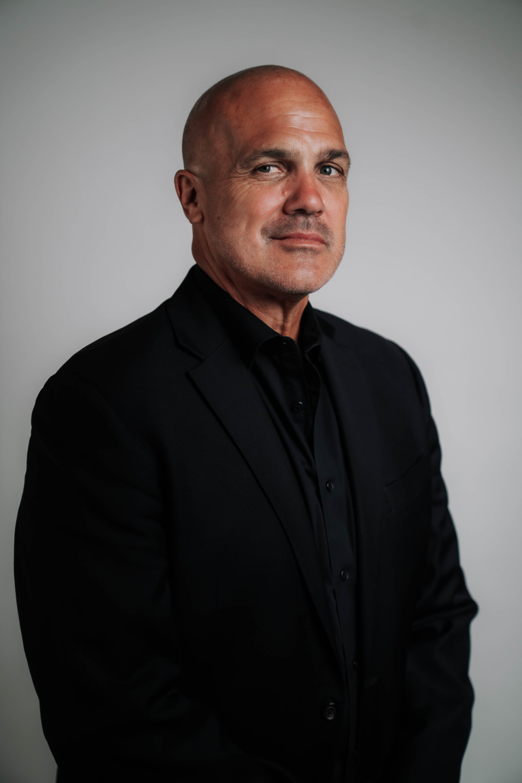 A confident professional headshot of Layne Ryan, Chief Executive Officer of Advine Agency. Layne presents a commanding presence in a sharp dark suit, reflecting leadership and expertise in agency management.