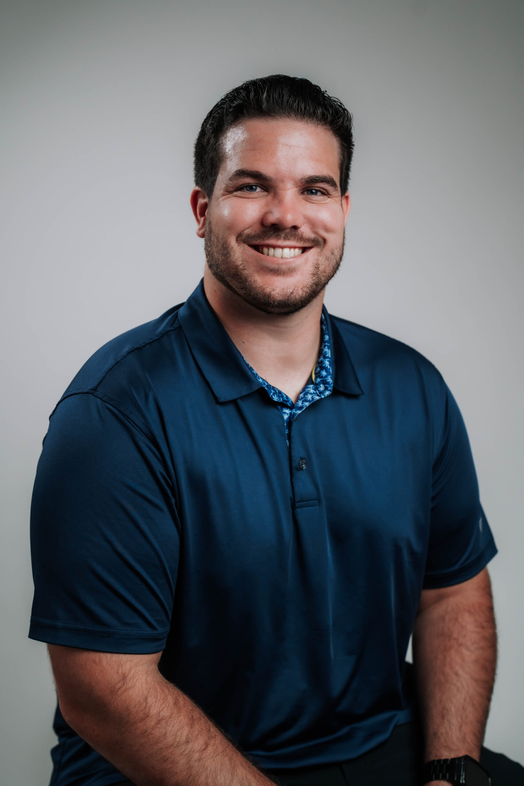 A dynamic professional headshot of Trevor Ryan, Business Development for Advine Agency. Trevor's confident, broad smile and professional blue polo showcase his passion for forging strong client partnerships and driving business growth.