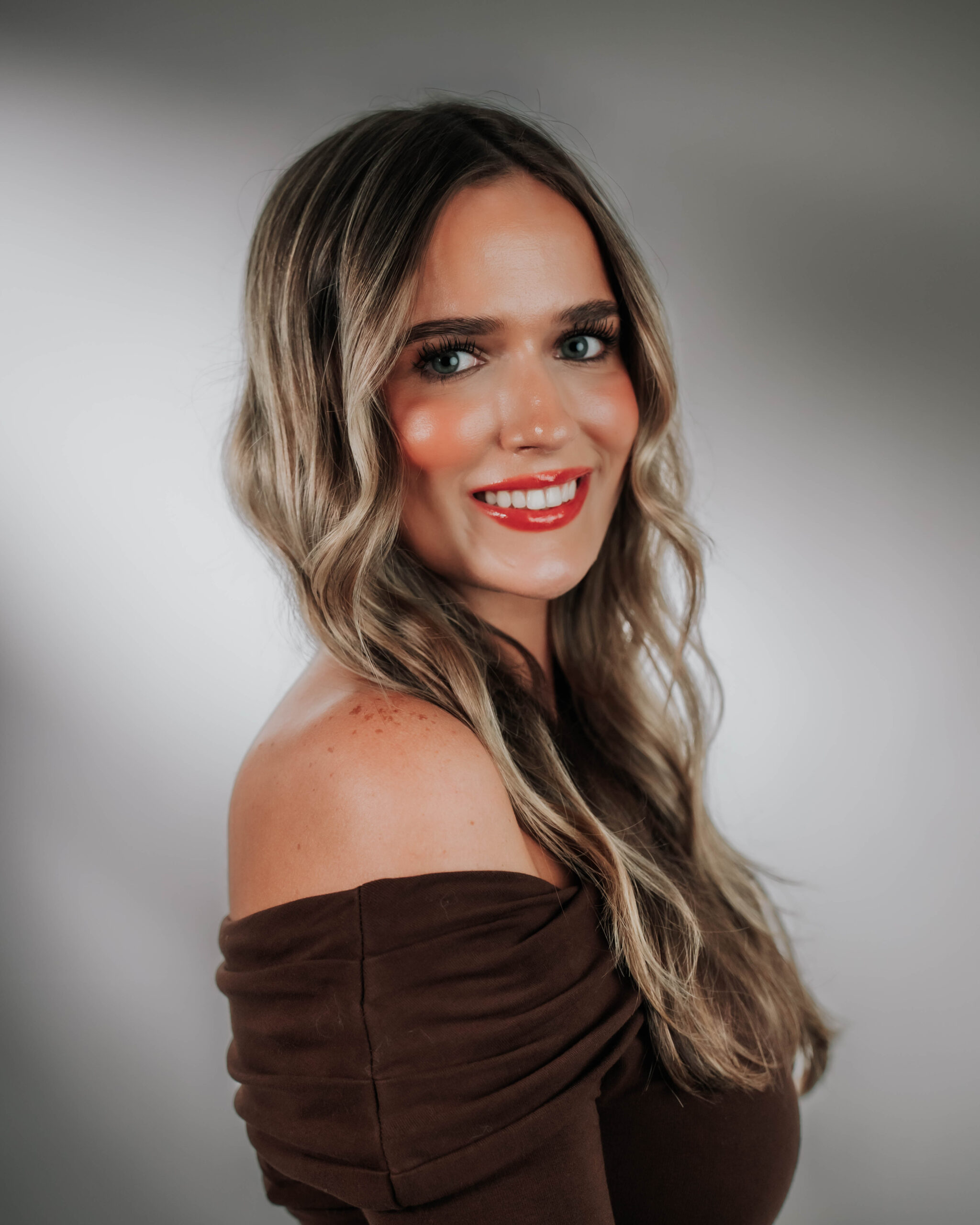 A stunning professional headshot of Lauren Cubre, Executive Assistant & AI Marketing Specialist for Advine Agency. Lauren's vibrant smile and modern off-the-shoulder top reflect her innovative approach and mastery of AI-driven marketing and executive support.