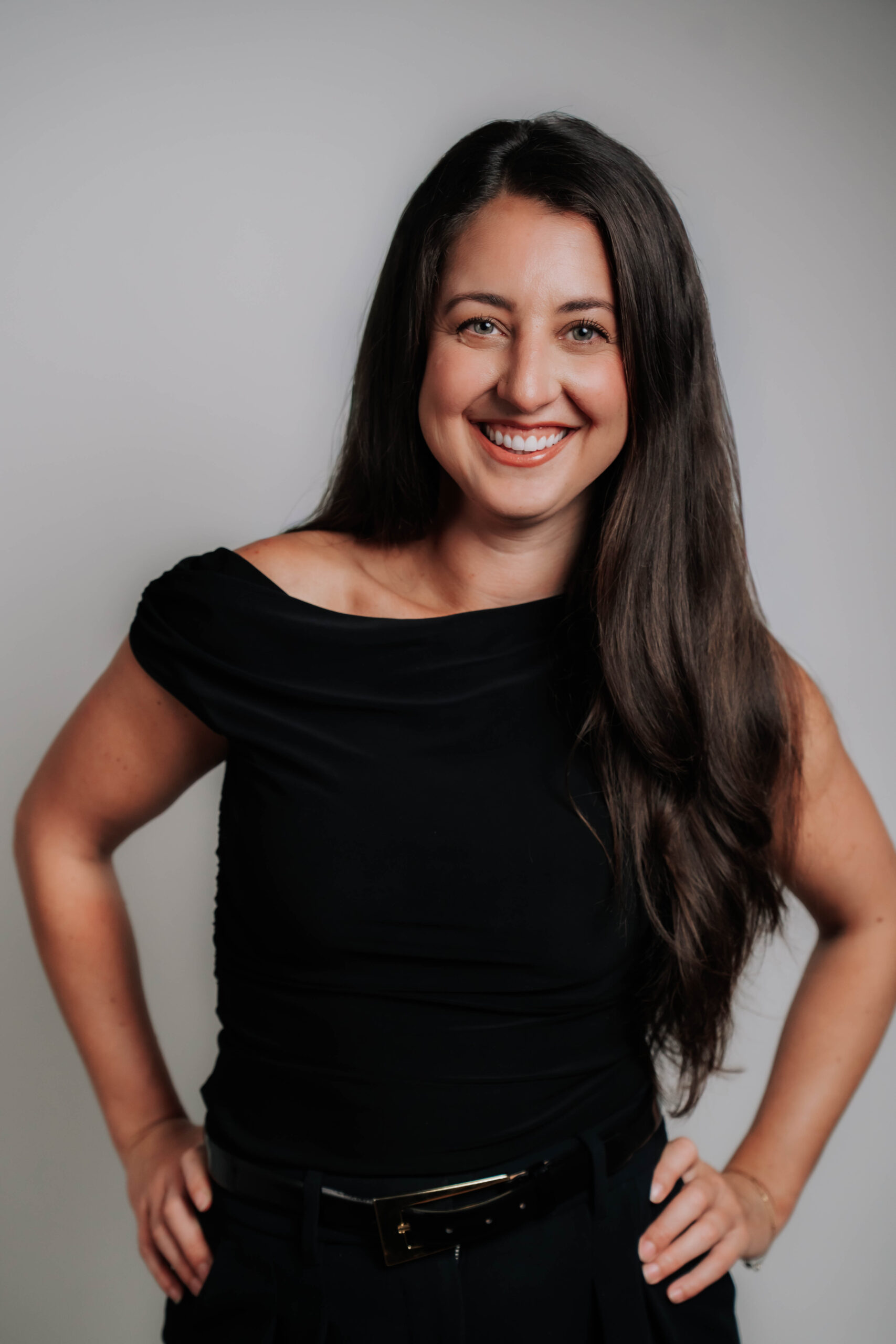 A vibrant professional headshot of Danielle Netzel, Chief Operating Officer at Advine Agency. Danielle, with her warm smile and stylish black off-the-shoulder top, embodies approachable leadership and strategic operational excellence.