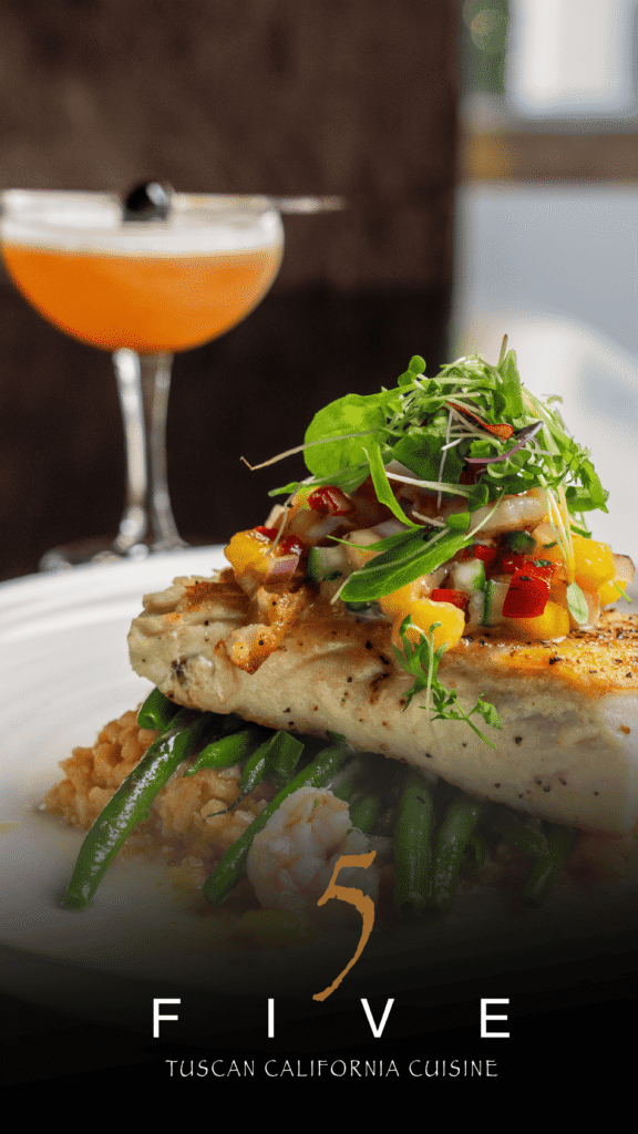 Five Restaurant Advine's photography captures a perfectly plated dish of Tuscan California Cuisine from FIVE Restaurant, featuring grilled fish topped with salsa, green beans, and a side of rice, with a stylish cocktail in the soft-focus background.