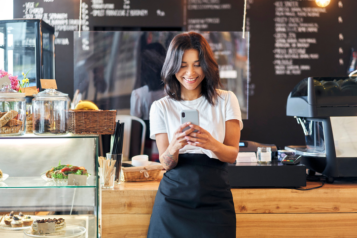 Posting social media Portrait of smiling waitress barista posting on social media for their business