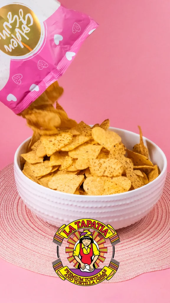 Advine's vibrant studio shot for La Tapatia shows golden tortilla chips pouring from a pink "Golden Sun" bag into a white bowl against a bright pink backdrop, highlighting the "Premium Tortilla Chips."
